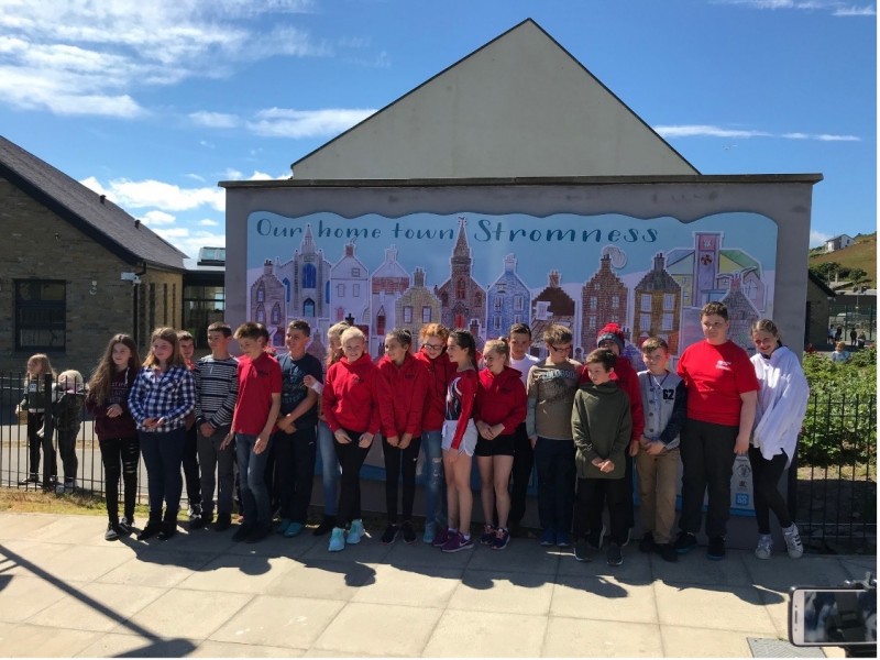 Unveiled on the 2nd of July 2018, the P7 pupils proudly stand in front of their fantastic mural. Image credit: Stromness Museum