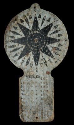 A wooden traverse board used in navigation, with painted detail. The holes in the board are for pegs.